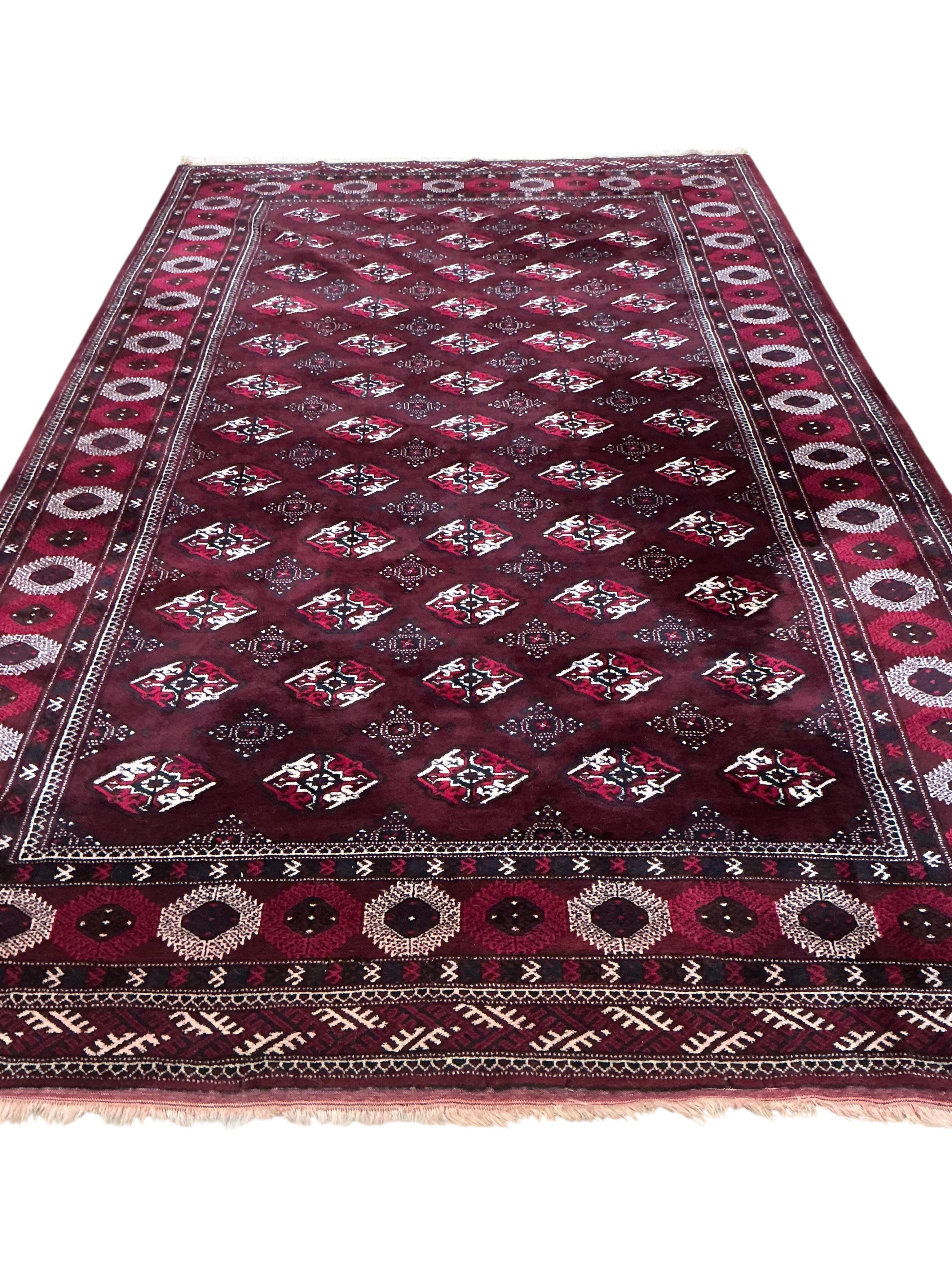 A Turkoman burgundy ground carpet, 386 x 234cm